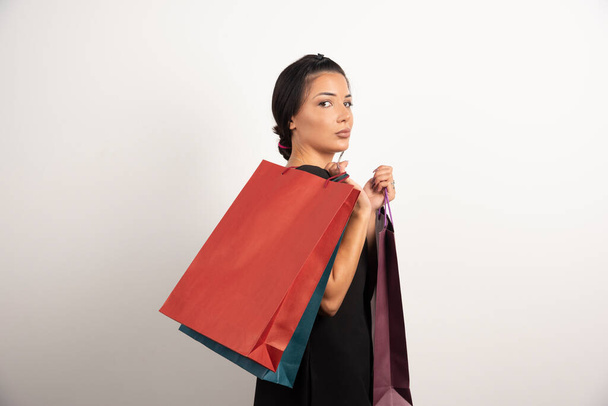 Σοβαρή γυναίκα με τσάντες για ψώνια σε λευκό φόντο. Υψηλής ποιότητας φωτογραφία - Φωτογραφία, εικόνα