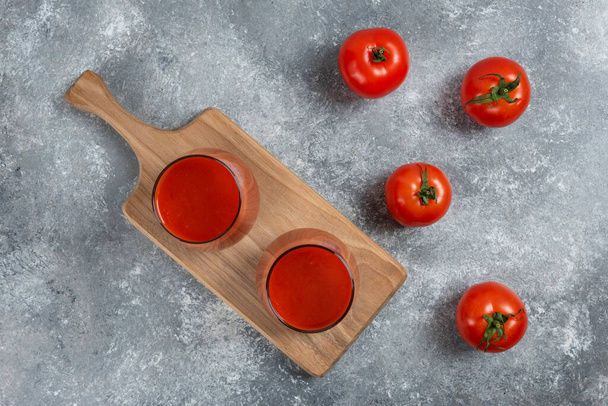 Deux tasses de jus de tomate sur une planche de bois. Photo de haute qualité - Photo, image