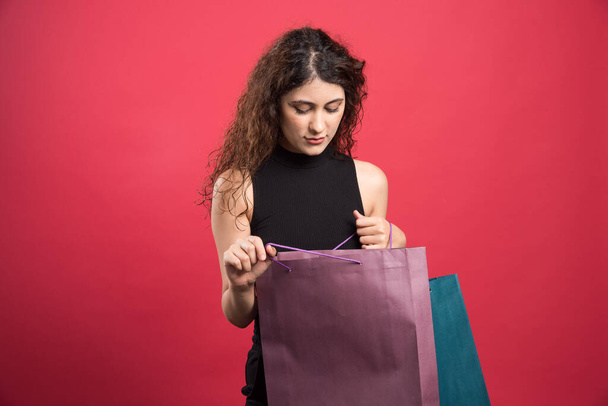 Mujer mirando una bolsa sobre fondo rojo. Foto de alta calidad - Foto, imagen