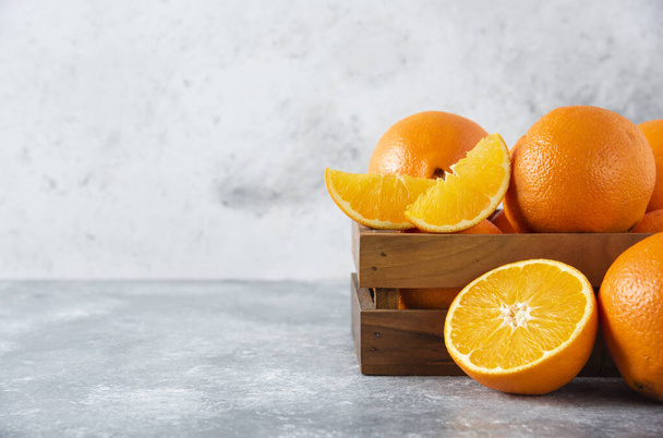 Egy régi fadoboz tele szaftos narancsos gyümölcsökkel kőháttéren. Kiváló minőségű fénykép - Fotó, kép