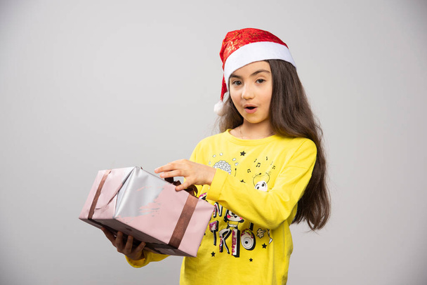 A Mikulás piros sapkás gyerek karácsonyi ajándékkal a kezében. Kiváló minőségű fénykép - Fotó, kép