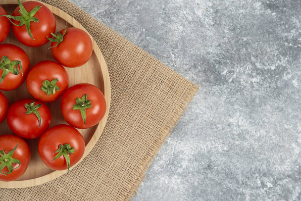 Assiette en bois de tomates biologiques fraîches sur fond de marbre. Photo de haute qualité - Photo, image