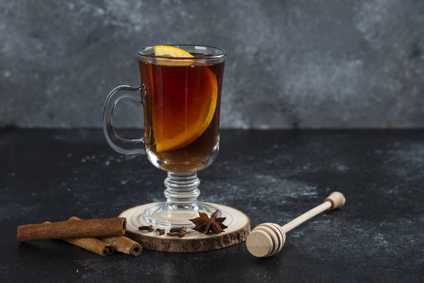 A glass cup of tea and with cinnamon sticks and wooden dipper . High quality photo - Photo, Image