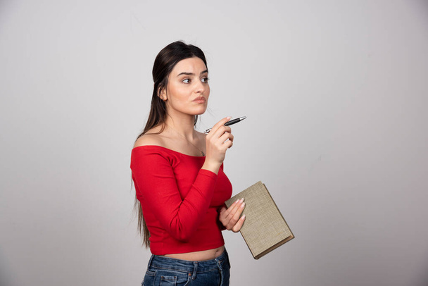 Portrait of a pensive woman holding a book. High quality photo - Foto, afbeelding