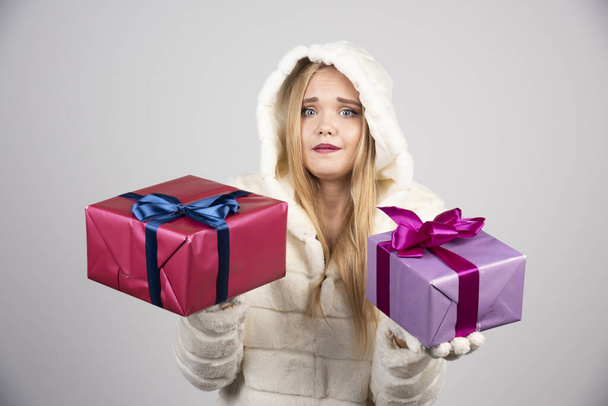 Blonde woman happily offering gift boxes. High quality photo - Fotografie, Obrázek