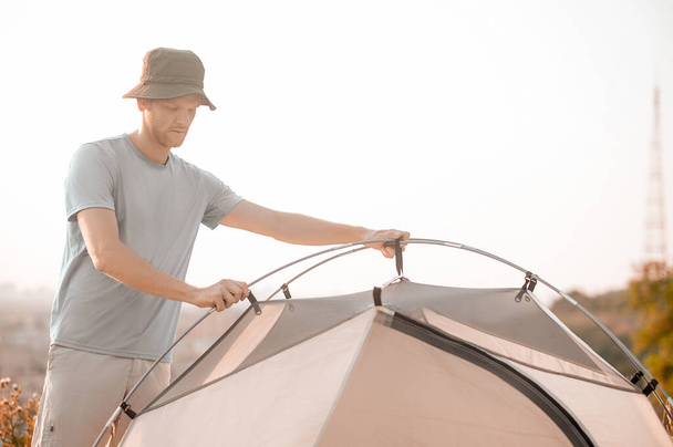 Une photo d'un jeune homme ayant l'air occupé à planter la tente - Photo, image