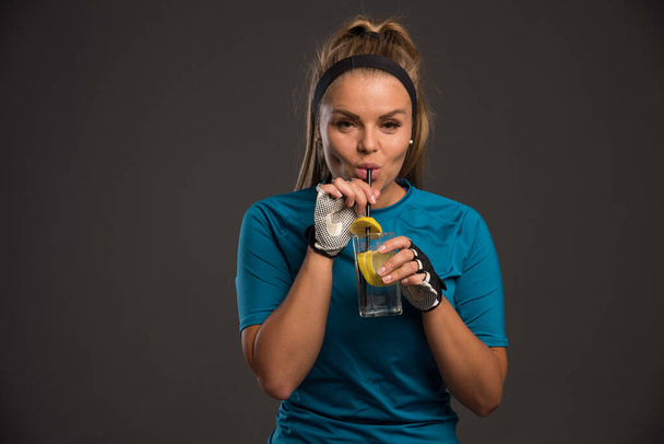 Mujer deportiva joven tomando bebida energética con limón después del entrenamiento. Foto de alta calidad - Foto, Imagen