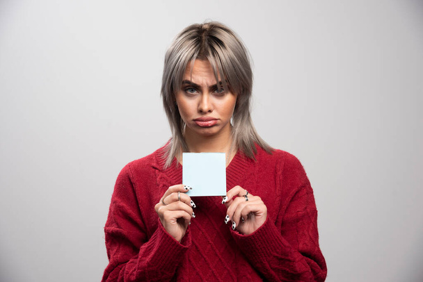 Mujer triste sosteniendo bloc de notas sobre fondo gris. Foto de alta calidad - Foto, Imagen