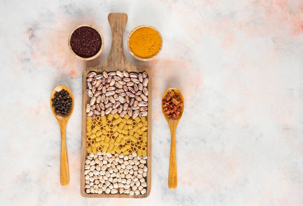 Куча зерновых продуктов на деревянной доске. Бин, паста и горох со специями. Высокое качество фото - Фото, изображение