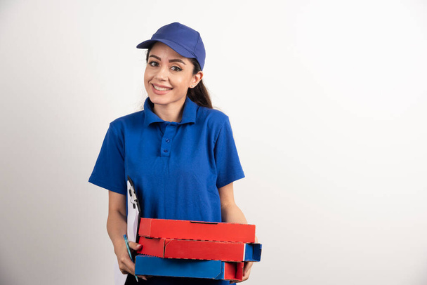 Mensajería femenina positiva con cartón de pizza y portapapeles  - Foto, imagen