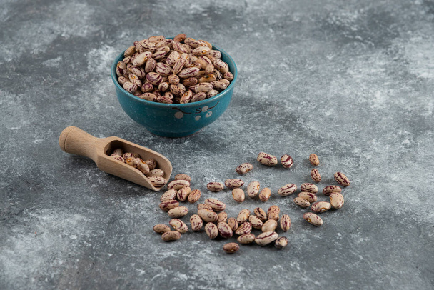 Bowl of dry beans and wooden spoon on marble background. High quality photo - Foto, Bild