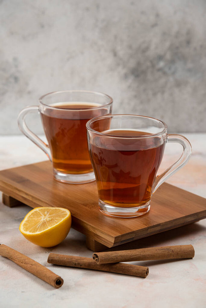 Two cups of hot tea on wooden board with cinnamon sticks. High quality photo - 写真・画像
