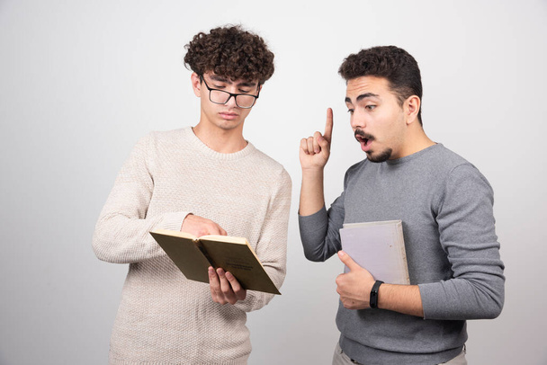 Two young men holding books on a white background. High quality photo - Photo, Image