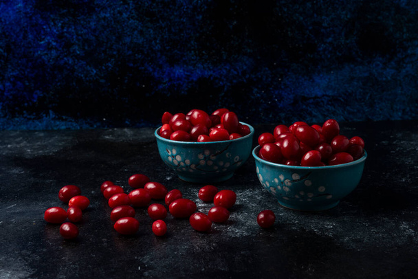 Cornels in blue cups on black background. High quality photo - Foto, Imagen