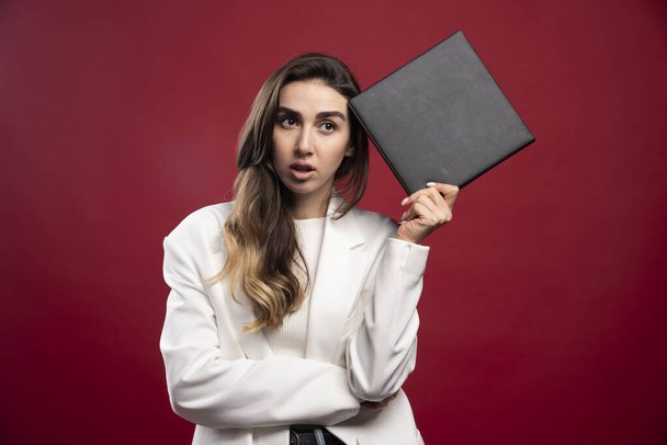 Business woman holding a notebook on a red background. High quality photo - Photo, Image