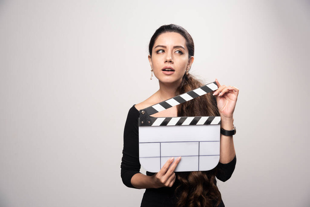 A filmmaker girl holding an open clapper board and looking confused or overthinking. High quality photo - Photo, Image