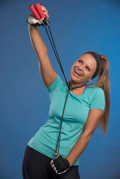 Młoda sportowa kobieta dławi się skakankami i uśmiecha. Wysokiej jakości zdjęcie - Zdjęcie, obraz