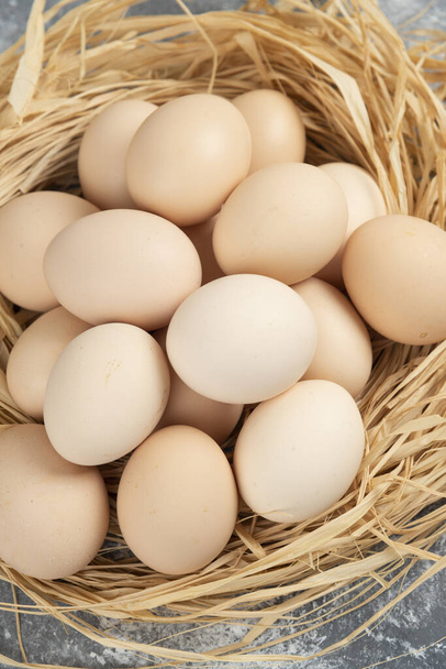 Raakoja munia, joissa on linnunpesä marmoripinnalla. Laadukas kuva - Valokuva, kuva