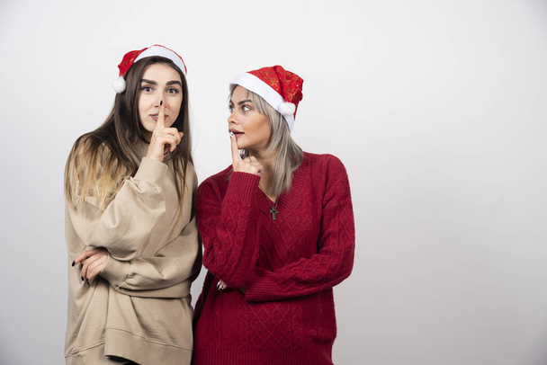 Twee jonge meisjes in Santa hoed staan en poseren. Hoge kwaliteit foto - Foto, afbeelding