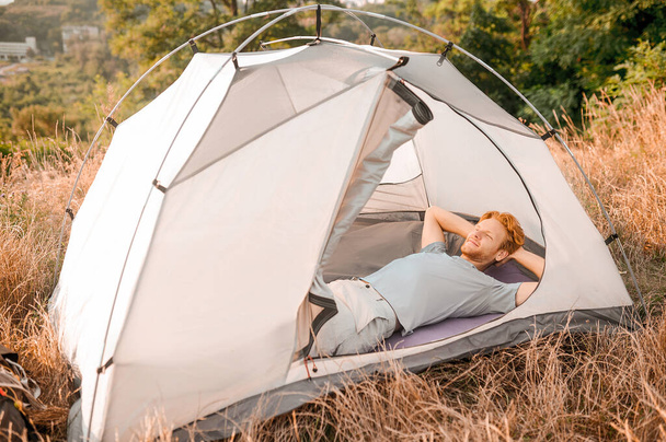 Un uomo steso nella sua tenda e assonnato - Foto, immagini