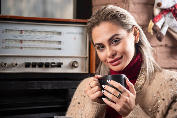 Usmívající se žena sedící a držící šálek kávy nebo čaje. Kvalitní fotografie - Fotografie, Obrázek
