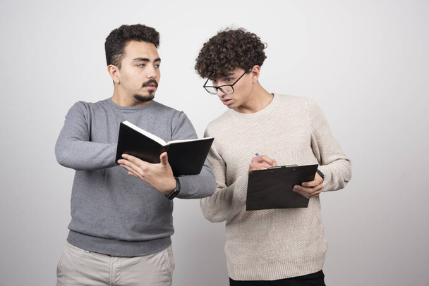 Two young men holding notebooks with pencils. High quality photo - Fotografie, Obrázek