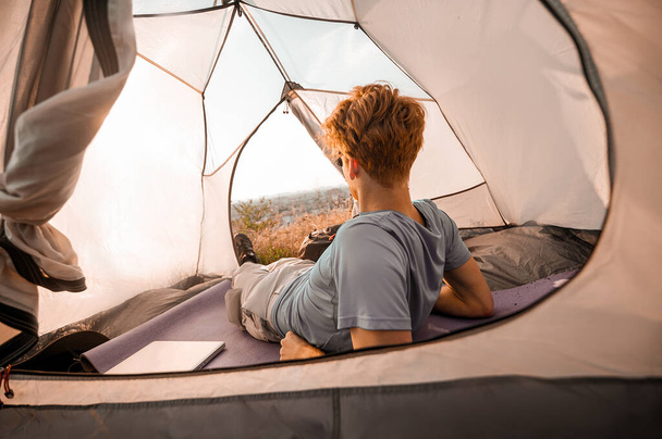 Un homme roux se sent bien et couché dans une tente - Photo, image