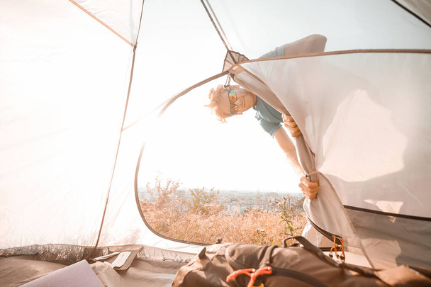 Um homem passando o fim de semana em um campo olhando ocupado consertando a tenda - Foto, Imagem