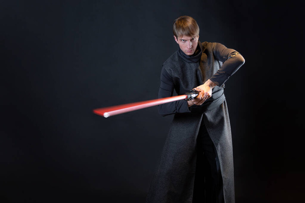 A villain with a red lightsaber, a young man in a long robe does fighting poses, - Φωτογραφία, εικόνα