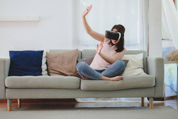 VRヘッドセットを使用して興奮アジアの女性リビングルームで自宅で仮想現実 - 写真・画像