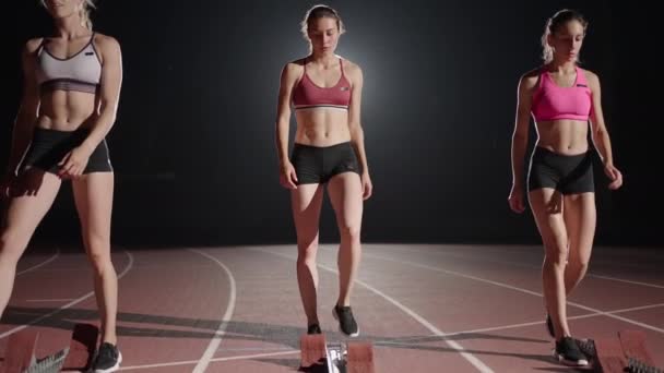 Young pretty women jogging in sportswear and sneakers getting ready for the race on the jogging track together. Start from the line and start the race in slow motion in the dark - Footage, Video