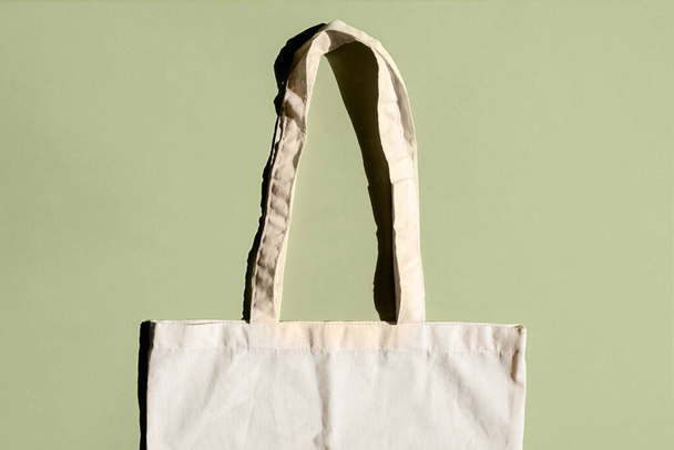Reusable cotton shopping bag on green and beige background. Zero waste concept. No plastic - Фото, зображення