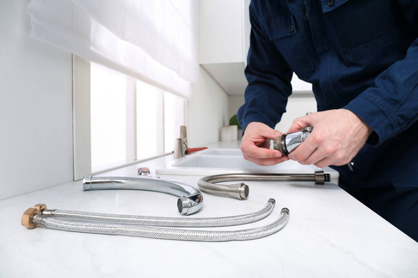 Professional plumber fixing water tap in kitchen, closeup - Fotoğraf, Görsel