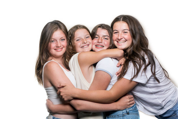 Eine Gruppe von vier kaukasischen Teenagermädchen, lässig gekleidet, lachend, amüsiert, isoliert auf weißem Hintergrund - Foto, Bild