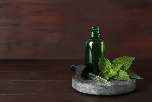 Glass bottle of nettle oil with dropper and leaves on wooden table. Space for text - Foto, Bild