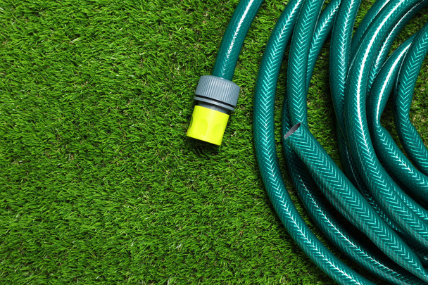 Watering hose on green grass, top view. Space for text - Фото, зображення