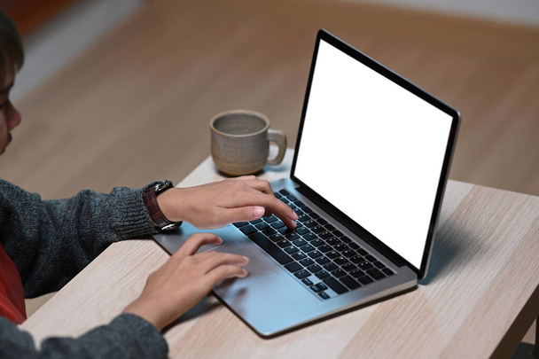 Recortado tiro de la mujer de diseño está trabajando en el ordenador portátil con pantalla en blanco en el escritorio de madera. - Foto, Imagen