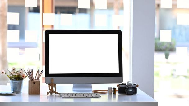 Frontansicht eines modernen Arbeitsplatzes mit Computer, Kamera und Anlage auf Holztisch. - Foto, Bild