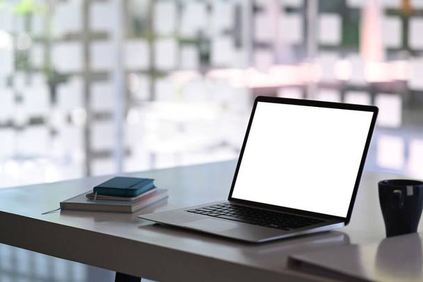Сучасний офісний стіл з ноутбуком, чашкою кави та блокнотом. Білий екран для введення тексту
. - Фото, зображення
