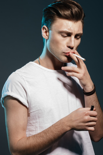 Handsome young man smoking cigarette - 写真・画像