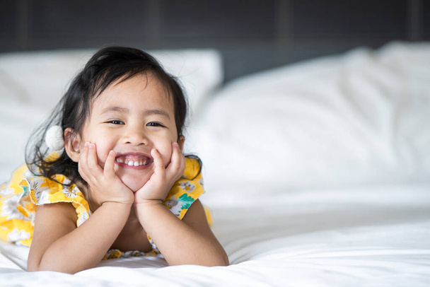 An Asian cheerful little girl lying on her bed ind - 写真・画像