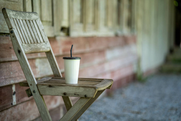 A white iced coffee cup on an antique wooden chair - Valokuva, kuva