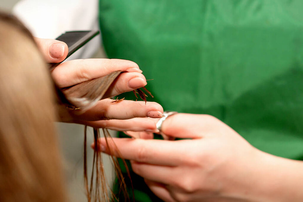 Closeup of a hairdresser cutting hair tips of a female customer in a beauty salon - Photo, Image