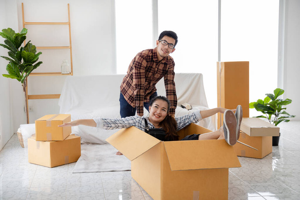 gelukkig jong aziatisch paar glimlachen ontspannen en het hebben van plezier tijdens het verhuizen naar nieuw huis - Foto, afbeelding