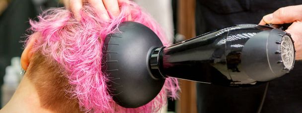 Mężczyzna fryzjer profesjonalne suszenie stylowe różowe włosy kobiety klient z suszarką do włosów w salonie piękności - Zdjęcie, obraz
