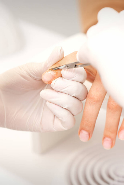 Zblízka manikúra mistr s manikúrou nůžky odstraňuje kůžičky ženských nehtů v salonu krásy - Fotografie, Obrázek