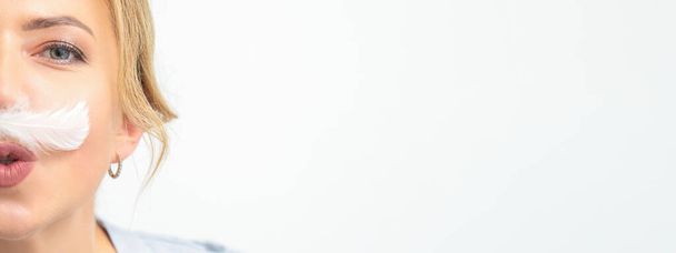Lustige Kosmetikerin mit einem weißen federartigen Schnurrbart posiert auf weißem Hintergrund, Enthaarungskonzept - Foto, Bild
