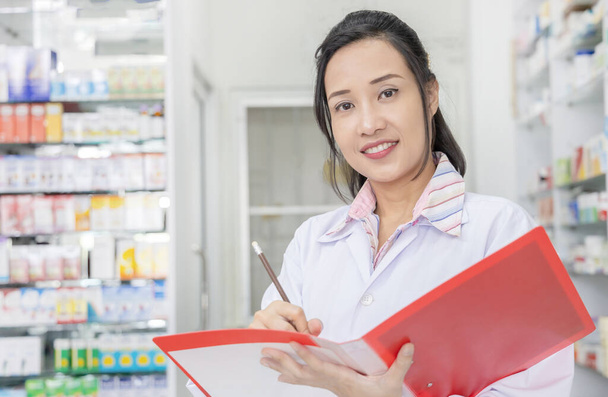 Asian female pharmacist checking  stock of the medicine in drugs - Photo, Image