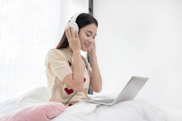   Asian female freelancer in headphones working on laptop at home - Photo, Image