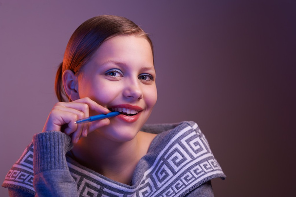 έφηβος κορίτσι χαμογελά με στυλό στο χέρι, πορτρέτο - Φωτογραφία, εικόνα